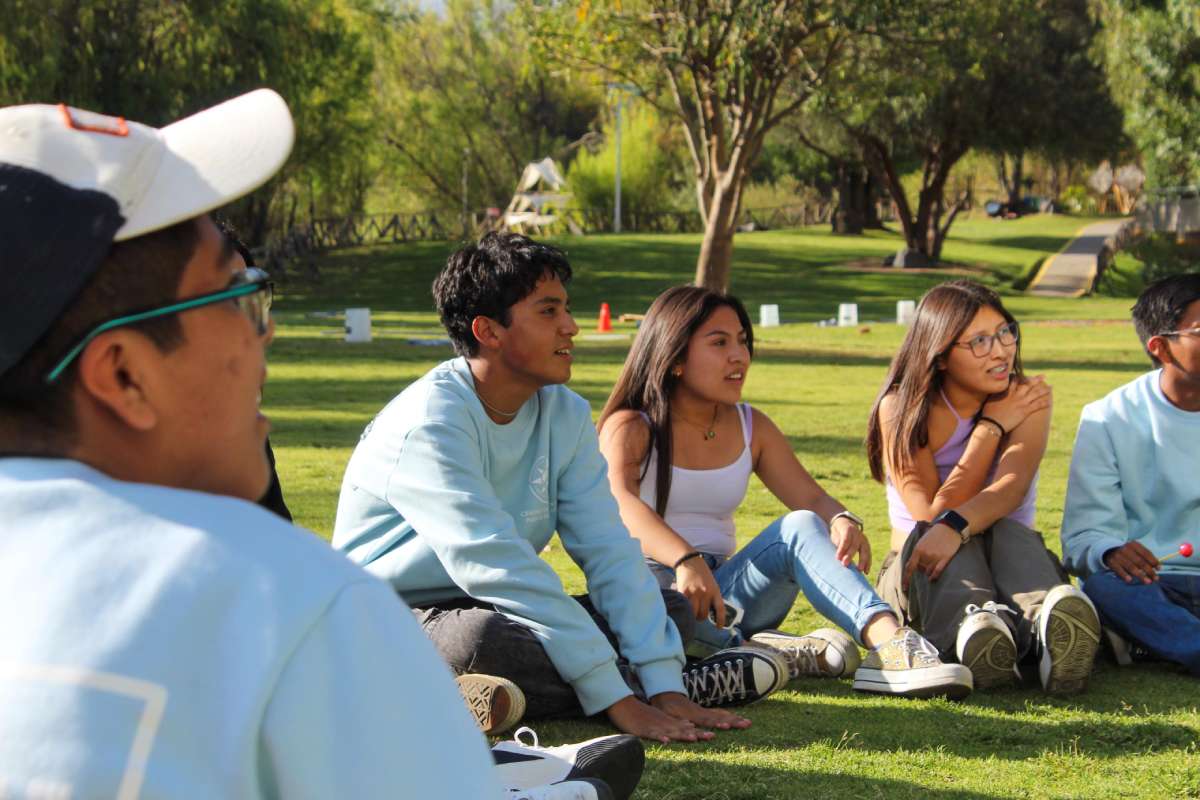 Chicos sentados en el pasto formando un círculo